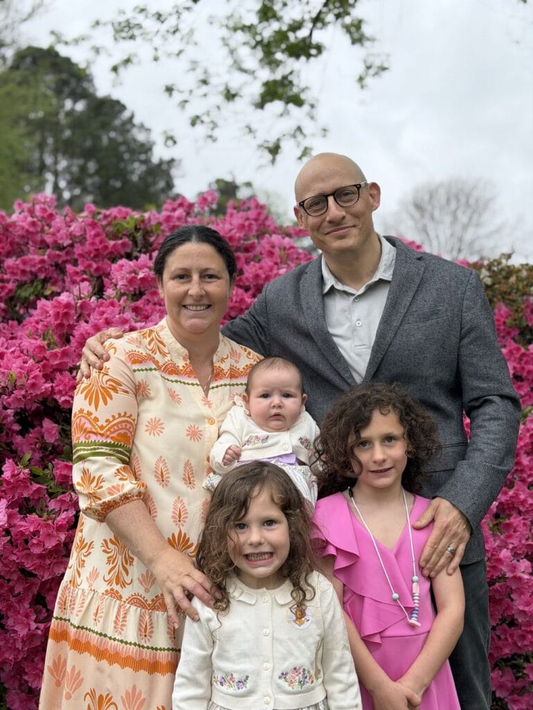 Adam Buice and his wife stand with their three children in front of a blooming pink azalea bush at Easter